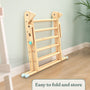The TP Toys TP Active-Tots Pikler Style Wooden Climbing Triangle & Slide—FSC® certified—folded and leaning against a light green wall on a wooden floor. Text in the corner reads, “Easy to fold and store.”.