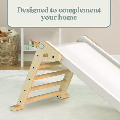 The TP Toys TP Active-Tots Pikler Style Folding Wooden Slide - FSC® certified, featuring white accents, is set up in a playroom with toys, a woven basket, and other Montessori items in the background.