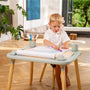 A young boy sits at a table drawing on a TP Active-Tots Play Table Paper Roll Accessory attached to the tabletop.