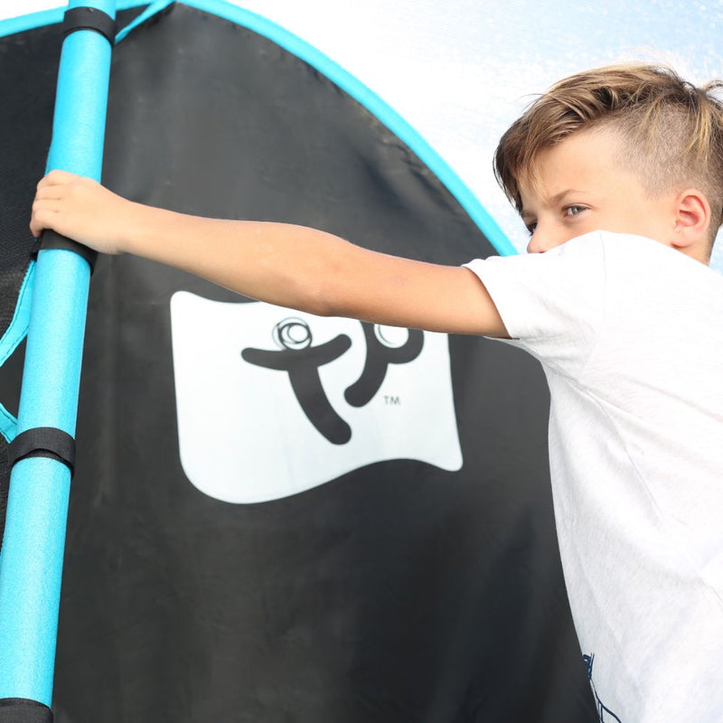 A child holding the blue padded pole of a TP Genius Blue 14ft Round Trampoline enclosure.