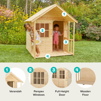 Two children play in the TP Toys TP Forest Cabin Wooden Playhouse—an FSC® certified garden cabin with a verandah, Perspex windows, and a full-height door—set on a grassy lawn among trees and bushes.
