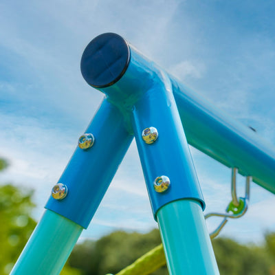 Close-up of the powder coated steel frame with bolts from the TP Double Metal Swing Set by TP Toys, shown outdoors against a blue sky and green blurred background.