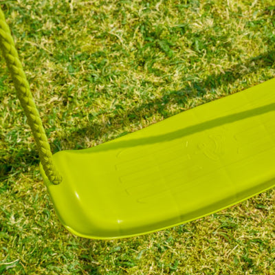 Close-up of a green injection-moulded swing seat hanging by ropes above grass, part of the TP Double Metal Swing Set from TP Toys with a powder coated steel frame.