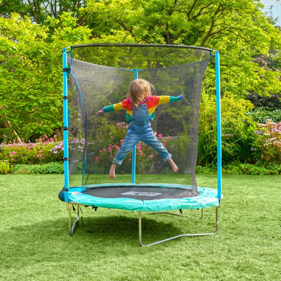 A child in a rainbow sweater and overalls jumps on the TP Toys TP UP 6ft Trampoline, which features a safety net, in a garden.