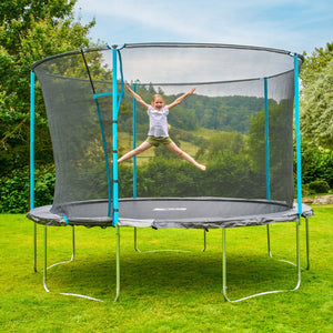 A child happily jumps with arms and legs outstretched on a TP Toys Up 12ft Trampoline, complete with safety net, enjoying active play in their grassy backyard.