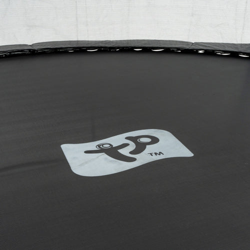 Close-up of a black TP Toys Up 12ft Trampoline surface, displaying a gray central logo with a stylized figure and the trademark symbol.