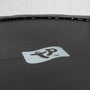 Close-up of a black TP Toys Up 12ft Trampoline surface, displaying a gray central logo with a stylized figure and the trademark symbol.