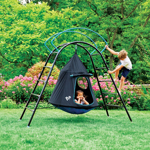 A child climbs the TP Toys TP UFO Den & Climbing Frame while another relaxes inside, surrounded by grass and pink flowers—a perfect garden play scene.