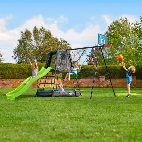 Four children play on a TP Toys TP Explorer Metal Climbing Frame Set & Ripple Slide, Swing and Basketball Black Edition outdoors. One shoots hoops while others climb or slide on the black edition frame set on the grass.
