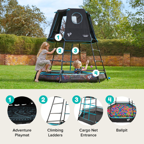 Two children play on the TP Toys Build Your Own TP Explorer Metal Climbing Frame Black Edition, which features a tent top, climbing ladders, a cargo net entrance, an adventure playmat, and a ball pit in a grassy yard.