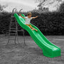 A young boy in a white shirt and yellow shorts slides down the bright green TP Toys 3m/10ft Super Wavy Slide in a grassy yard.