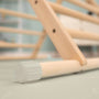 Close-up of the TP Active-Tots Pikler Style Wooden Climbing Triangle by TP Toys, an FSC® certified Montessori toy, showing a rounded plastic cap on one rod and set on a light-colored indoor floor.