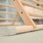 Close-up of the TP Active-Tots Pikler Style Wooden Climbing Triangle & Slide by TP Toys, featuring light wood bars and plastic end caps. FSC® certified, shown indoors on a soft, light-colored floor mat.