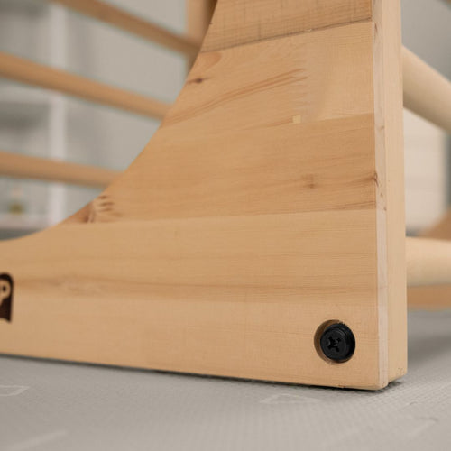 Close-up of the TP Active-Tots Pikler Style Wooden Climbing Cube by TP Toys, made from FSC® certified light wood, showing a visible black screw in the corner on a gray surface.