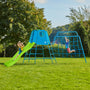 Two children play on the TP Toys Explorer Metal Climbing Frame with 8ft Ripple Slide and Monkey Bridge, enjoying the features in a grassy yard surrounded by trees under a clear sky.