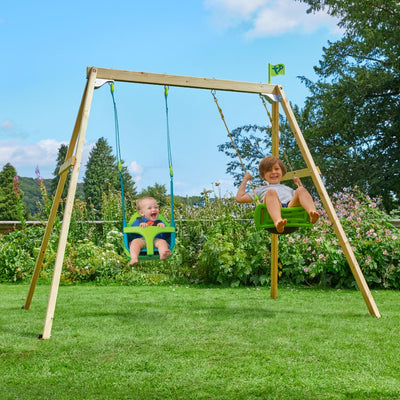 Two children play on the TP Toys TP Forest Wooden Double Swing with Quadpod and Roped Rapide Seats (FSC® certified), enjoying the garden’s greenery under a partly cloudy sky.