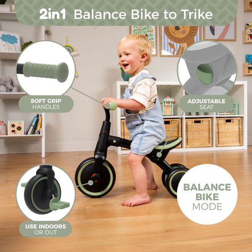 A toddler enjoys the Zoomee Balance Bike to Trike from TP Toys in black and green, featuring soft grip handles, an adjustable seat, indoor/outdoor versatility, and balance bike mode that supports child development.
