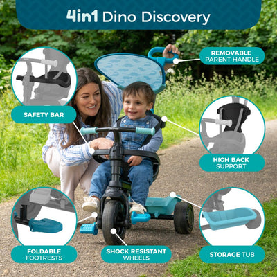 A woman kneels beside a young child on the TP Toys Zoomee 4 in 1 Trike - Dino Discovery, featuring a dinosaur print, safety bar, adjustable UV sunshade, foldable footrests, removable parent handle, high back support, storage tub, and shock-resistant wheels.