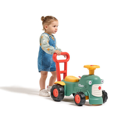 A young child holds the walking aid bar of the Falk Maurice Vintage Baby Green Tractor by TP Toys, featuring large wheels and a red steering wheel—ideal for learning to walk.