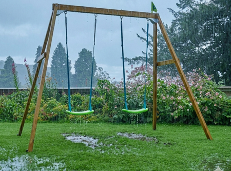 A forest wooden swing set in the rain