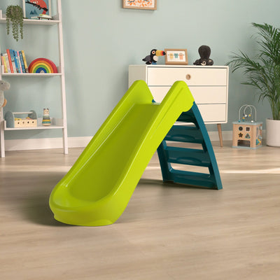 The TP Toys PalPlay Green & Blue Plastic Folding First Slide stands in the center of a playroom with wooden floors and toys neatly arranged on shelves.