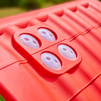 Close-up of a red plastic surface with four clear suction cups in a square pattern—ideal for securing parts of the TP Toys Palplay Plastic Dream Playhouse indoors or outdoors.