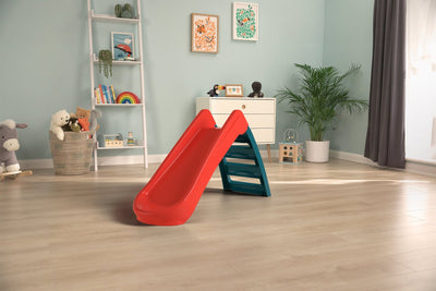 The TP Toys PalPlay Red & Blue Plastic Folding First Slide is set in the center of a playroom with light wood floors, toys, and a white dresser.