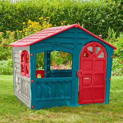 The TP Toys Palplay Plastic Playhouse of Fun features a red roof, blue and gray walls, a red door, and a window, perfect for outdoor play on grass with plants or bushes nearby.