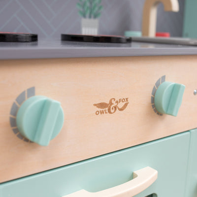 Close-up of the Owl & Fox Wooden Imagination Kitchen Set by TP Toys, featuring teal knobs, a handle, and logo on FSC®-certified wood—perfect for pretend play kitchen fun.
