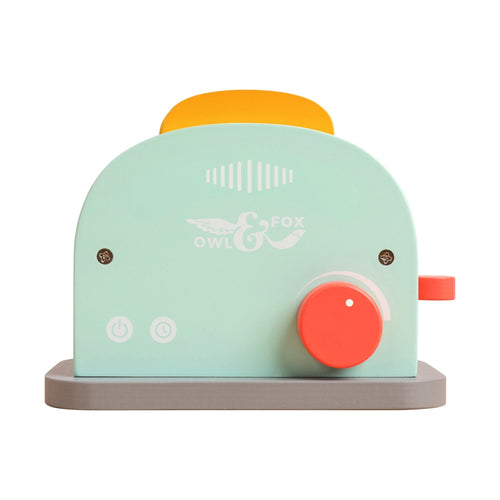 The TP Toys Owl & Fox Wooden Toaster Set (FSC® certified) features pastel colors, a red dial, orange lever, power buttons, and a yellow wooden toast slice—ideal for pretend play or as a charming Montessori toy.