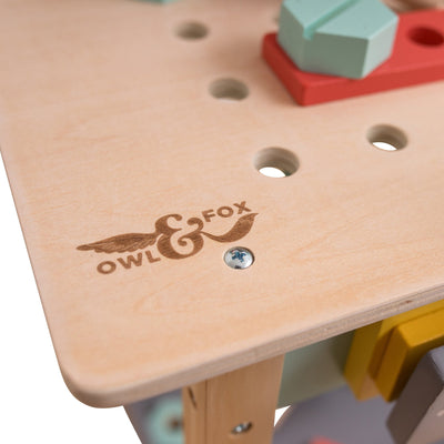 The Owl & Fox Wooden Workbench Set by TP Toys features an FSC® certified wooden surface with logo, visible screw, and colorful geometric blocks for imaginative Montessori-inspired pretend play.