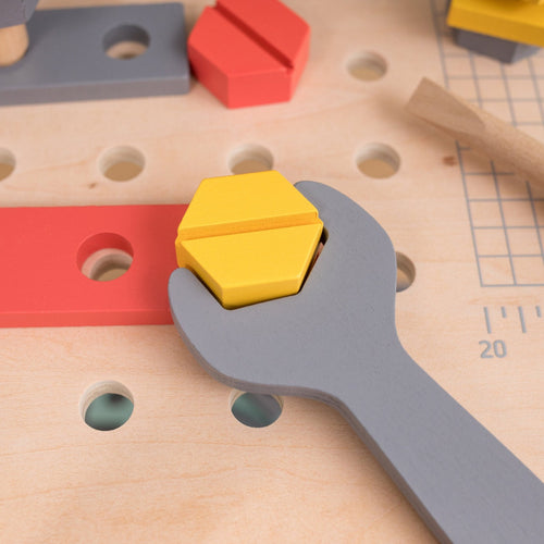 The TP Toys Owl & Fox Wooden Workbench Set (FSC® certified) features a gray wooden toy wrench holding a yellow hexagonal nut on a pegboard—ideal for pretend play and Montessori-inspired tool bench activities.