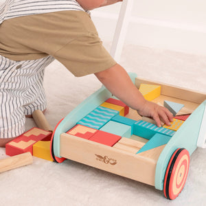 A child plays with colorful wooden blocks from the TP Toys Owl & Fox Wooden Baby Walker and Blocks - FSC® certified, on a light carpet.