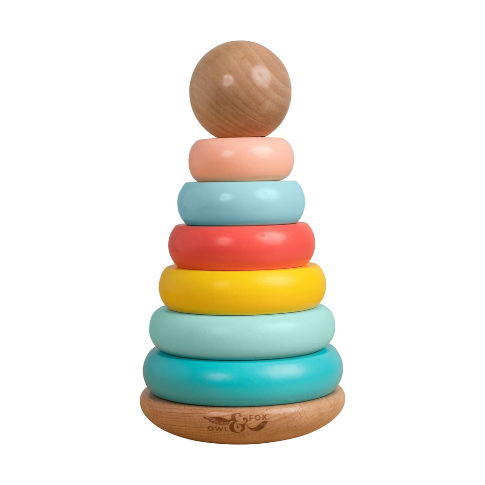 The Owl & Fox Wooden Topple Tower by TP Toys is an FSC® certified Montessori toy designed to boost hand-eye coordination, featuring a round top and six colorful rings stacked from largest to smallest.