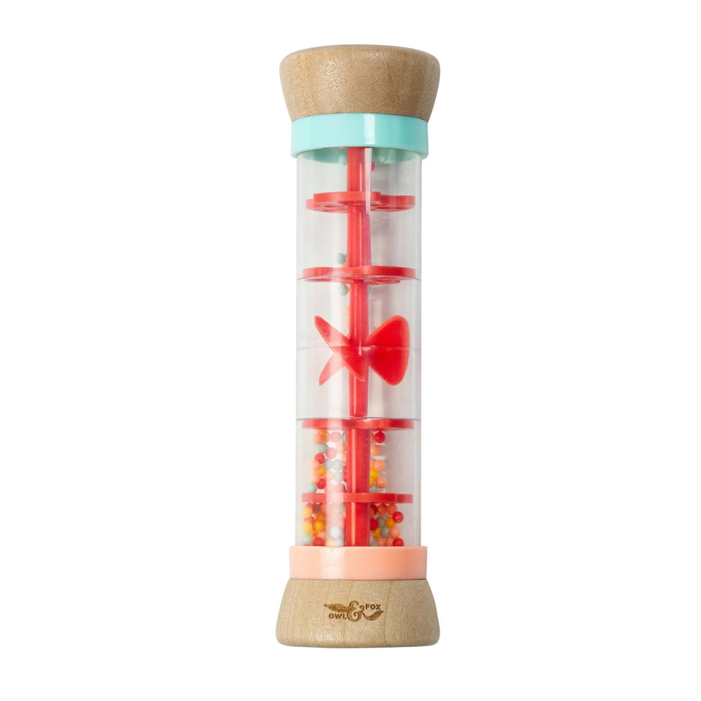 The Owl & Fox Wooden Rainmaker by TP Toys features a clear cylindrical design, colorful plastic components, and small beads inside. FSC® certified, it’s perfect for sensory development and musical play.