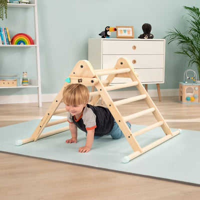 A child explores and builds new skills on the TP Active-Tots Pikler Style Wooden Climbing Triangle by TP Toys, a fun, FSC® certified indoor climber inspired by Montessori play.