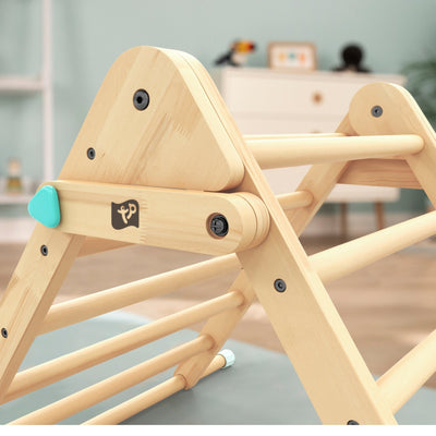 Close-up of the TP Toys TP Active-Tots Pikler Style Wooden Climbing Triangle—FSC® certified—for children, featuring a turquoise knob, set in a softly blurred, modern room background.