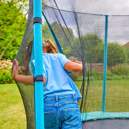 A girl stands on a TP Up 12ft Trampoline by TP Toys in the garden.