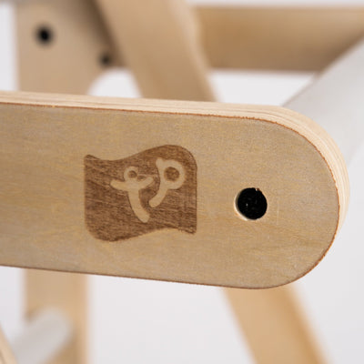 Close-up of the TP Toys Active-Tots Pikler Style Wooden Folding Helper Tower With Play Easel & Play Mats (FSC® certified), showcasing the etched logo and a nearby black screw hole.