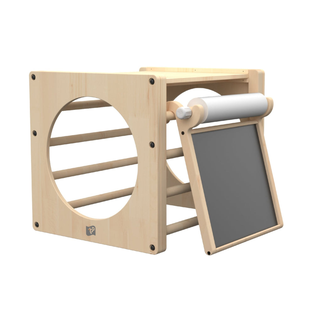 The TP Toys TP Active-Tots Pikler Style Wooden Climbing Cube With Play Easel (FSC® certified) features circular openings, horizontal bars, a chalkboard, and a paper roll—ideal for toddlers in any indoor play area.