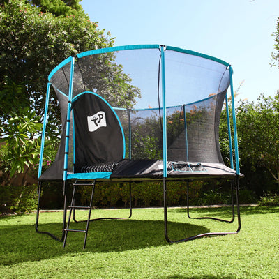 The TP Toys TP Genius® 12ft Round Trampoline Bundle, featuring a SurroundSafe enclosure and ladder, stands on a grassy lawn with its galvanised steel frame blending into the backdrop of trees and bushes.