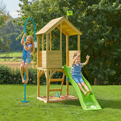 Two children play on the grass, exploring the TP Toys Treehouse Wooden Play Tower—FSC® certified—with a wavy slide, fireman’s pole, and a playhouse.