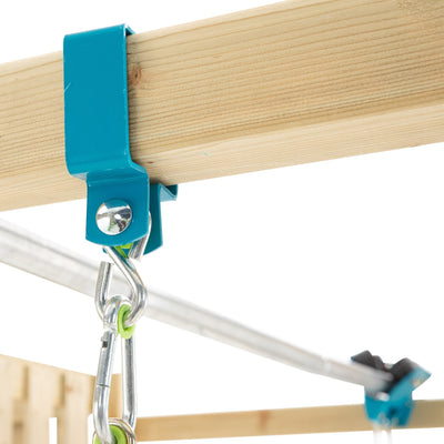 Close-up of a blue metal bracket securing a wooden beam on the TP Toys Skywood Wooden Tower Climbing Frame, with carabiners and hooks attached. Features include Ripple Slide, Sky Deck, Skyline & Flying Fox Add On. FSC® certified.