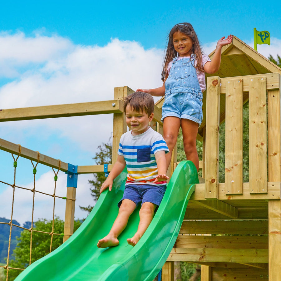 A boy and girl play on the TP Toys Skywood Wooden Tower Climbing Frame with Super Wavy Slide, Monkey Bars & Rapide Swing Seat, enjoying endless adventures on this modular FSC® certified playset.