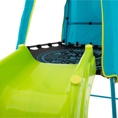 Close-up of the bright green Ripple Slide attached to the blue fabric den on the TP Explorer Metal Climbing Frame Set by TP Toys, featuring a black platform with white geometric designs and an included basketball hoop.