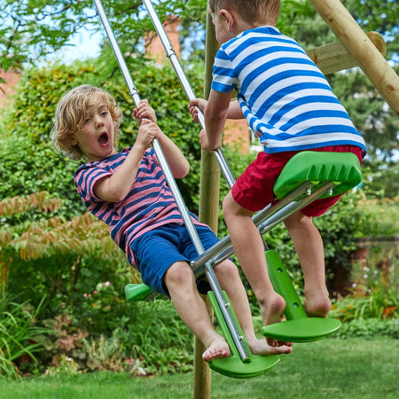 Two children enjoy the TP Sherwood Triple Wooden Swing Set with Glide Ride by TP Toys, PEFC certified, perfect for outdoor fun in small gardens.