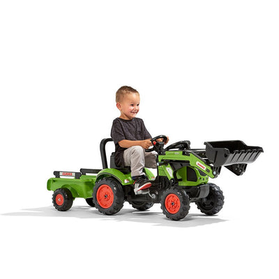 A young child smiles while riding a TP Toys Falk Class Backhoe with Trailer, a fun kids garden vehicle featuring a backhoe and attached trailer.