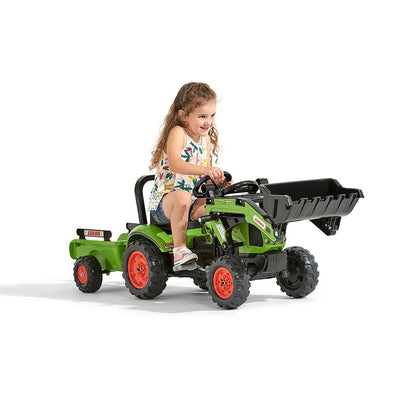 A young girl rides the TP Toys Falk Class Backhoe with Trailer—an exciting green ride-on toy featuring a front loader and trailer—against a white background.