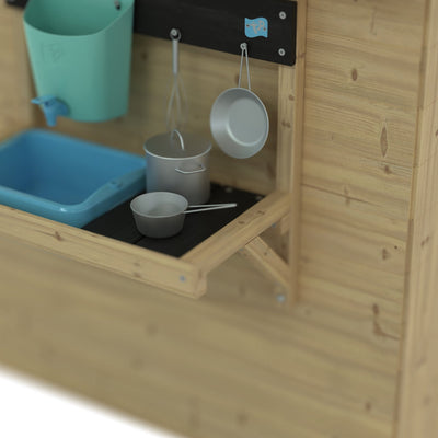 The Foxglove Cottage Playhouse by TP Toys includes an Early Fun Mud Kitchen Accessory made from FSC® certified wood, with toy pots, pans, utensils, a blue bucket, and a blue wall-mounted basin.
