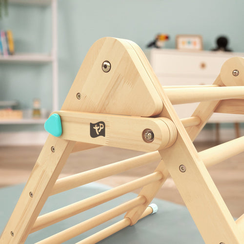 Close-up of the TP Toys TP Active-Tots Pikler Style Wooden Climbing Triangle, Cube & Slide – FSC® certified, a popular Montessori toy, shown indoors with blurred furniture in the background.